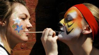 girl paints tiger on another girls face